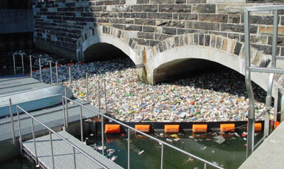 The bridge with masses of trash floating under it, contained by a floating wall