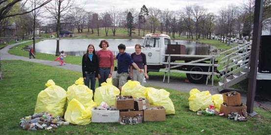 At a community pond, volunteers stand behind bags and boxes of collected litter