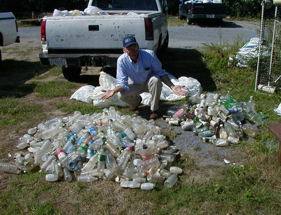 A man points to a large pile of beverage bottles and a small pile of bottles