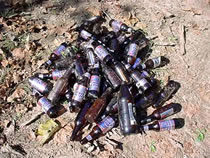 A pile of littered beer bottles in the sand